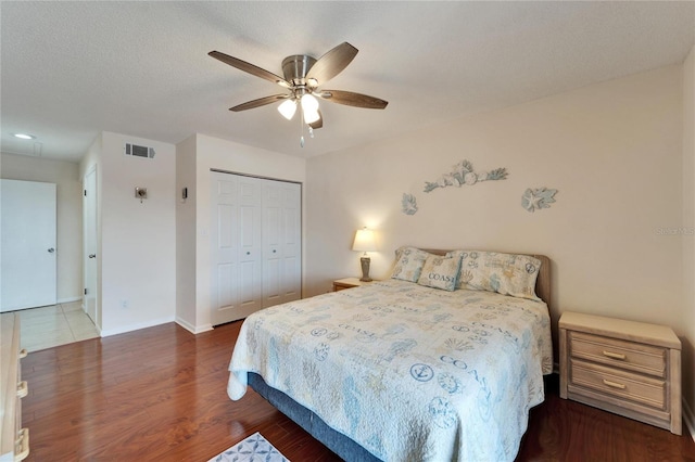 bedroom featuring a closet, wood finished floors, a textured ceiling, baseboards, and visible vents