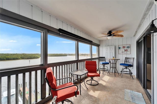 sunroom / solarium with a water view and a ceiling fan