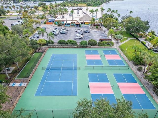 view of tennis court featuring a water view and fence