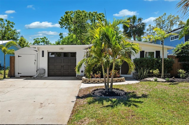 view of front of home with a garage, fence, stucco siding, a front lawn, and driveway