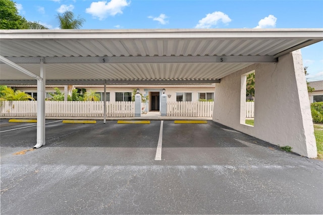 covered parking lot featuring fence