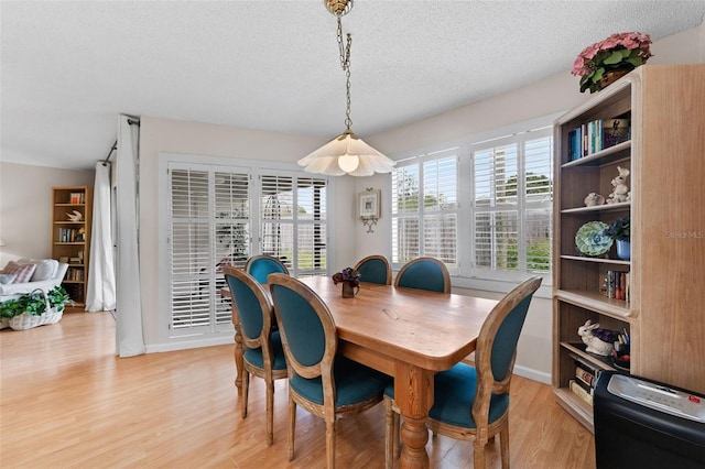 dining area with a textured ceiling and light wood-style floors