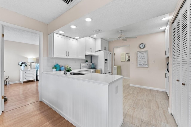 kitchen with a textured ceiling, light countertops, white appliances, ceiling fan, and a sink