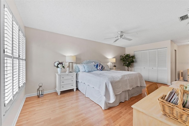 bedroom with a closet, a textured ceiling, visible vents, and light wood-style floors