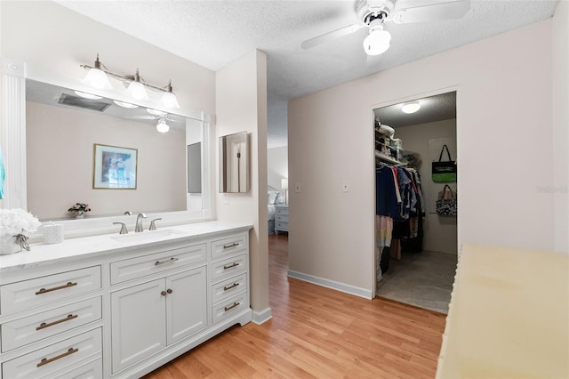bathroom featuring a textured ceiling, visible vents, ceiling fan, wood finished floors, and vanity