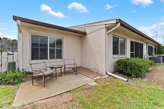 back of house with stucco siding, central air condition unit, and a patio
