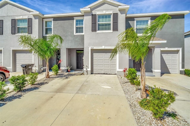 view of front facade with a garage, driveway, and stucco siding
