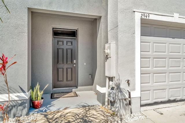 doorway to property featuring stucco siding and a garage