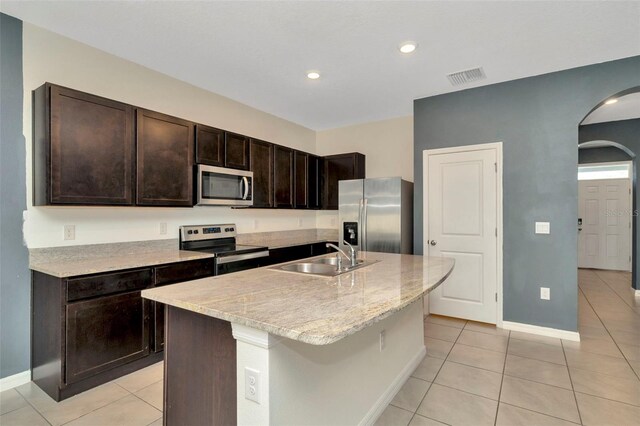 kitchen featuring a sink, arched walkways, visible vents, dark brown cabinets, and appliances with stainless steel finishes