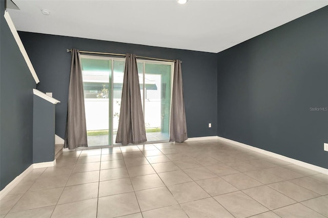 spare room featuring baseboards and light tile patterned floors