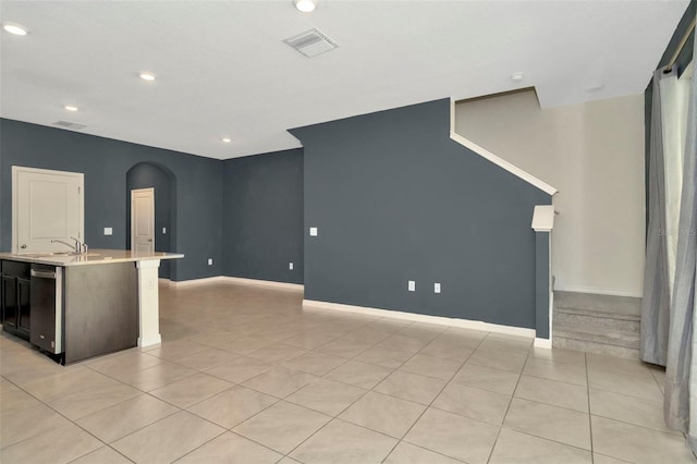unfurnished living room with light tile patterned floors, arched walkways, baseboards, and visible vents