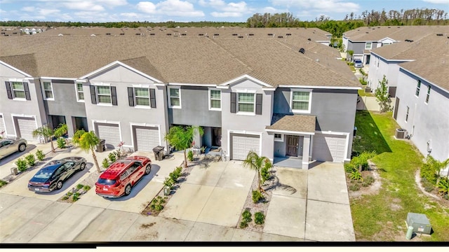 view of property featuring driveway, roof with shingles, stucco siding, a residential view, and a garage