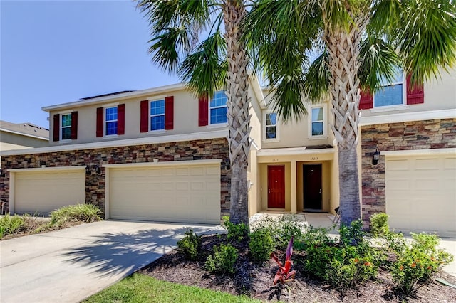 13217 Canopy Creek Dr, Tampa, FL 33625 - townhome / multi-family property with stucco siding, a garage, stone siding, and driveway