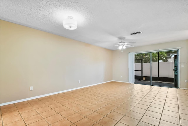 empty room featuring a textured ceiling, light tile patterned floors, ceiling fan, baseboards, and visible vents