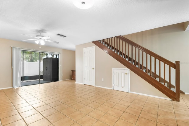 unfurnished living room featuring baseboards, visible vents, stairway, ceiling fan, and light tile patterned floors
