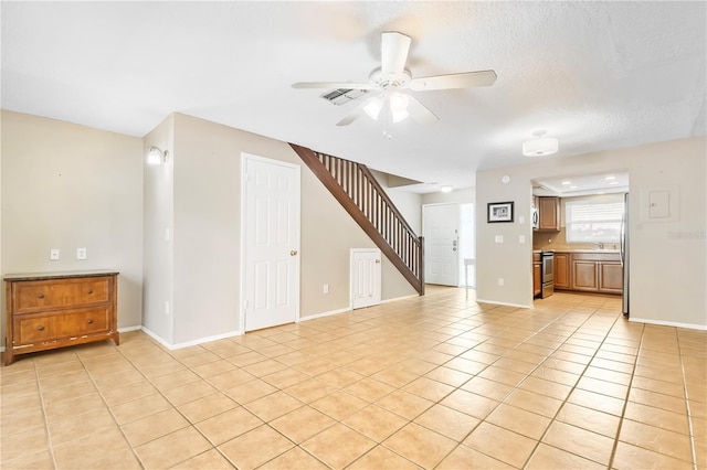 unfurnished living room featuring a ceiling fan, stairs, light tile patterned floors, baseboards, and visible vents