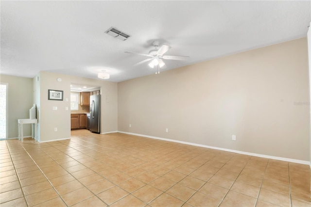 empty room featuring light tile patterned flooring, visible vents, baseboards, and ceiling fan