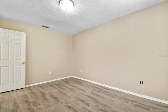 empty room featuring wood finished floors, a textured ceiling, and baseboards