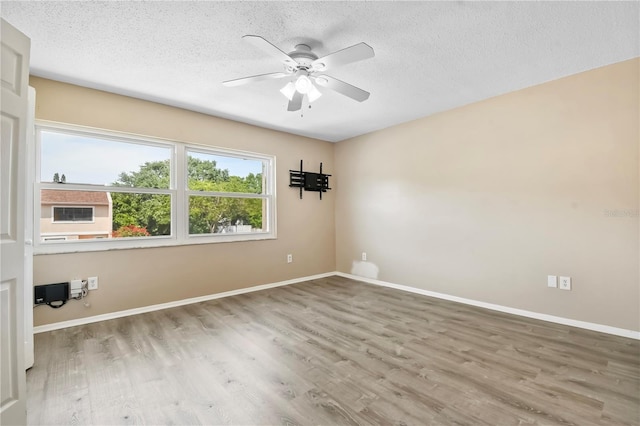 empty room featuring ceiling fan, baseboards, wood finished floors, and a textured ceiling