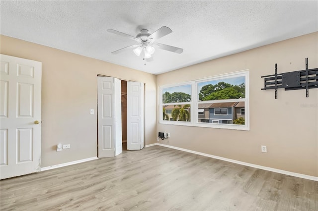 unfurnished bedroom with a ceiling fan, wood finished floors, a textured ceiling, a closet, and baseboards