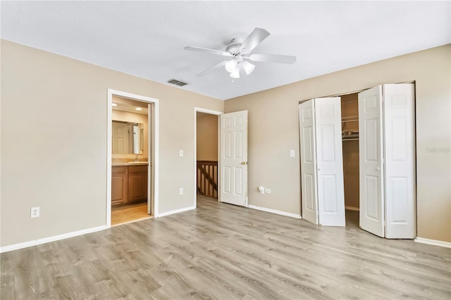 unfurnished bedroom with visible vents, light wood-style floors, a closet, baseboards, and ensuite bathroom