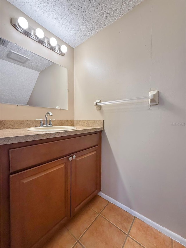 bathroom with tile patterned floors, baseboards, vanity, and a textured ceiling