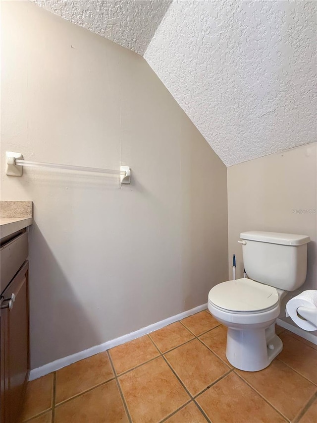 half bathroom with tile patterned flooring, vaulted ceiling, a textured ceiling, and toilet