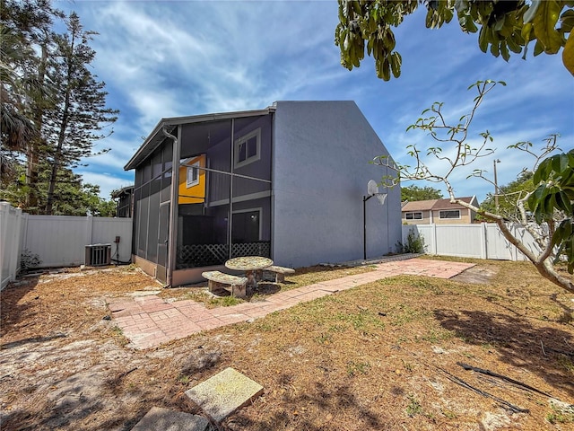 exterior space with a patio area, a fenced backyard, a sunroom, and central air condition unit