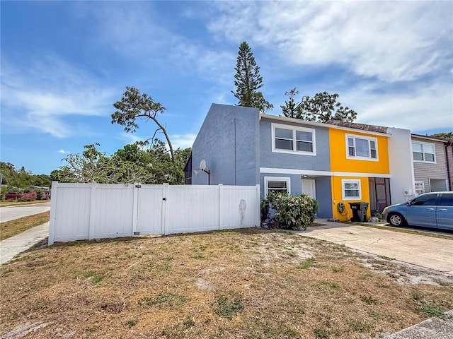 view of front of home with fence, a gate, and stucco siding