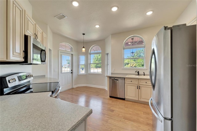 14807 Capps Estates Ln, Wimauma, FL 33598 - kitchen with stainless steel appliances, healthy amount of natural light, cream cabinets, light wood-type flooring, and recessed lighting
