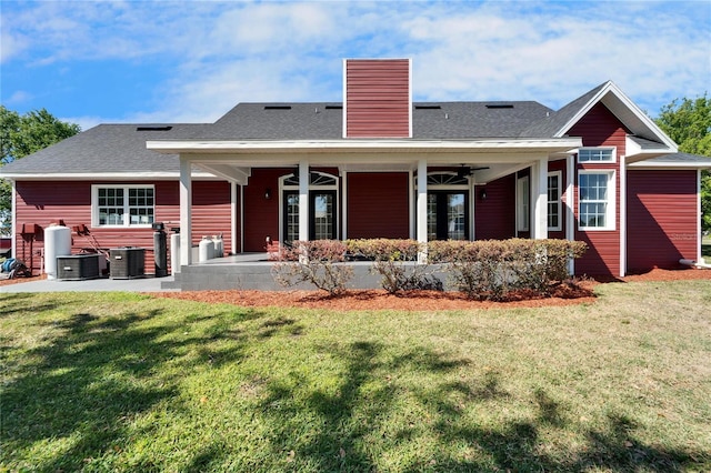 14807 Capps Estates Ln, Wimauma, FL 33598 - back of house with a ceiling fan, a lawn, a chimney, and a shingled roof