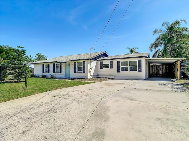 single story home featuring a front yard, an attached carport, and driveway