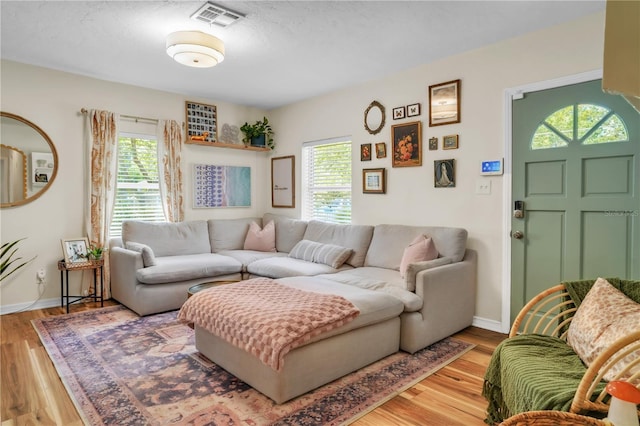 living room featuring visible vents, wood finished floors, and plenty of natural light