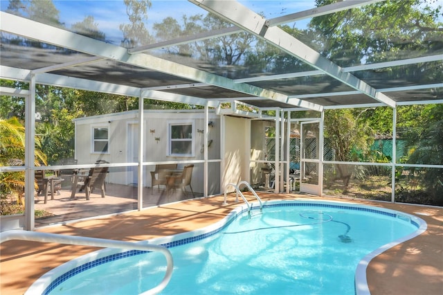 pool featuring glass enclosure, outdoor dining area, and a patio area