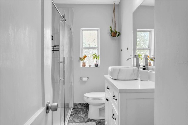 bathroom featuring marble finish floor, toilet, vanity, and a stall shower