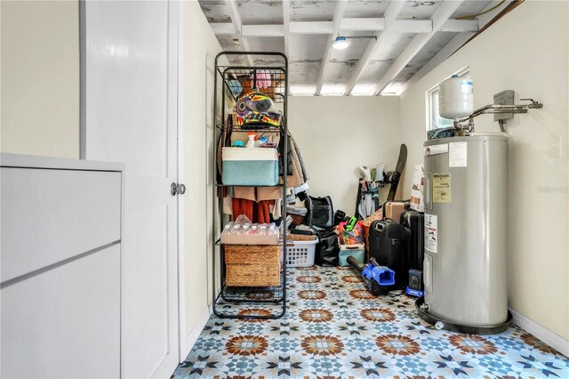 basement with water heater, tile patterned floors, and baseboards