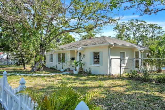 view of front facade featuring stucco siding, a gate, a front lawn, and fence private yard