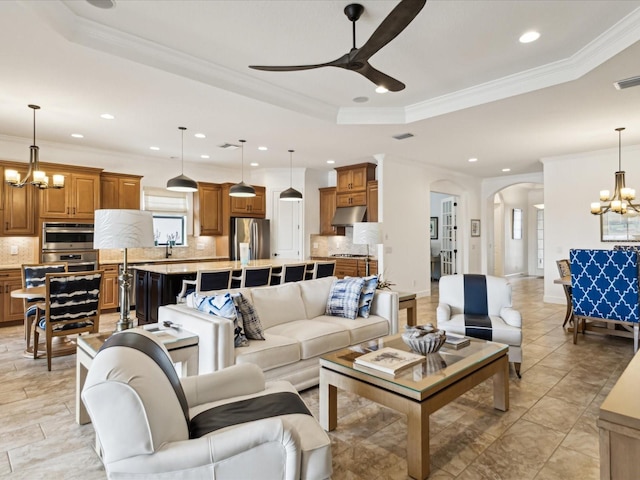 11248 Juglans Dr, Odessa, FL 33556 - living room featuring a tray ceiling, crown molding, recessed lighting, ceiling fan with notable chandelier, and arched walkways