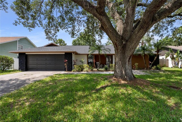 4715 Kemble Ct, Tampa, FL 33624 - ranch-style home featuring driveway, stone siding, fence, an attached garage, and a front lawn