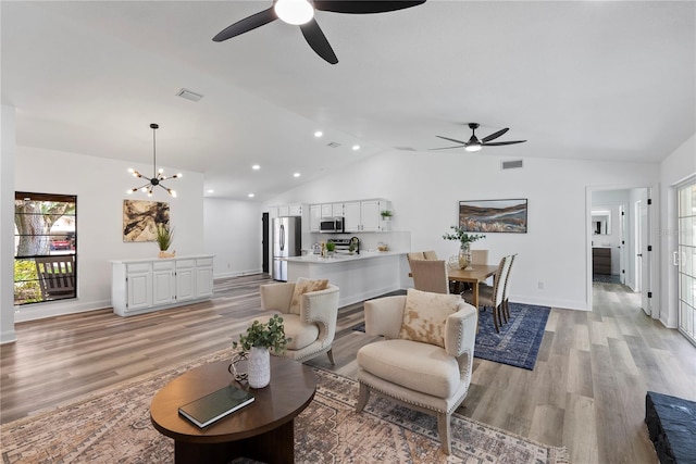 4715 Kemble Ct, Tampa, FL 33624 - living room featuring lofted ceiling, visible vents, light wood-style flooring, and ceiling fan with notable chandelier