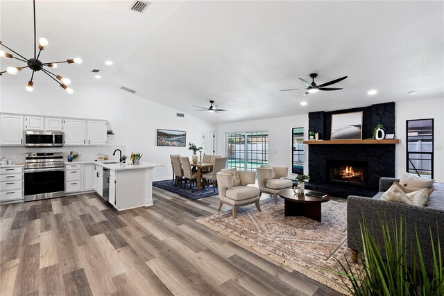 4715 Kemble Ct, Tampa, FL 33624 - living room with lofted ceiling, light wood-style flooring, a large fireplace, visible vents, and a ceiling fan