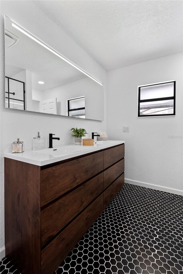 4715 Kemble Ct, Tampa, FL 33624 - bathroom with baseboards, a textured ceiling, a sink, walk in shower, and double vanity