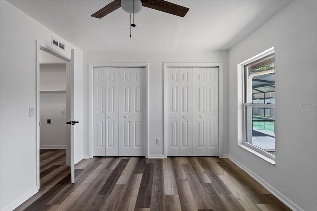 4715 Kemble Ct, Tampa, FL 33624 - unfurnished bedroom with visible vents, two closets, baseboards, ceiling fan, and dark wood-type flooring