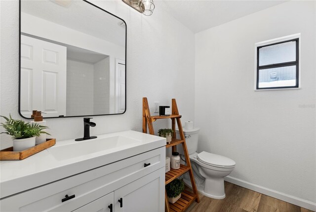 4715 Kemble Ct, Tampa, FL 33624 - half bathroom featuring toilet, vanity, baseboards, and wood finished floors