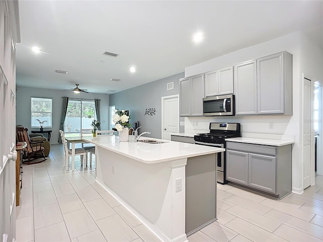 5415 Los Robles Ct, Palmetto, FL 34221 - kitchen featuring stainless steel appliances, gray cabinetry, a ceiling fan, an island with sink, and light countertops