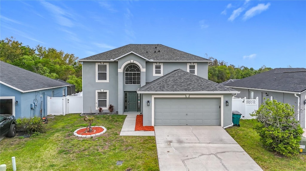 traditional-style home featuring stucco siding, a gate, a front yard, and roof with shingles