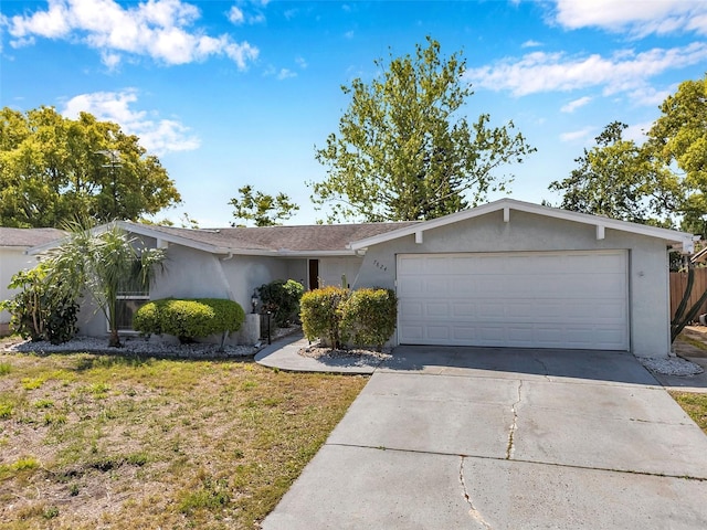 ranch-style home featuring a garage, a front lawn, stucco siding, and concrete driveway