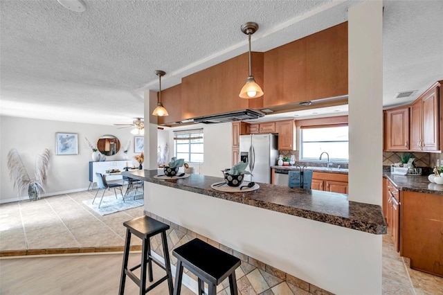 kitchen with a textured ceiling, dark countertops, appliances with stainless steel finishes, and a wealth of natural light