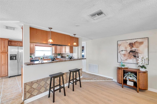 kitchen featuring stainless steel fridge, light wood-style flooring, and visible vents