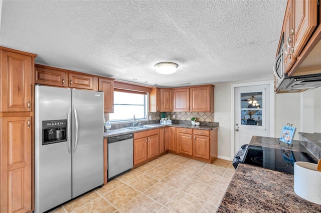 kitchen featuring a sink, a textured ceiling, appliances with stainless steel finishes, and brown cabinets